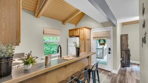 A modern kitchen with wooden beams, a bar area, and a view of the outdoors.