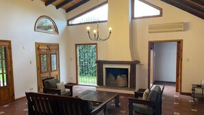 A spacious living room with a fireplace, wooden beams, large windows, and a tiled floor. - Casa Loria by Vilvey Turismo (Chacras de Coria)