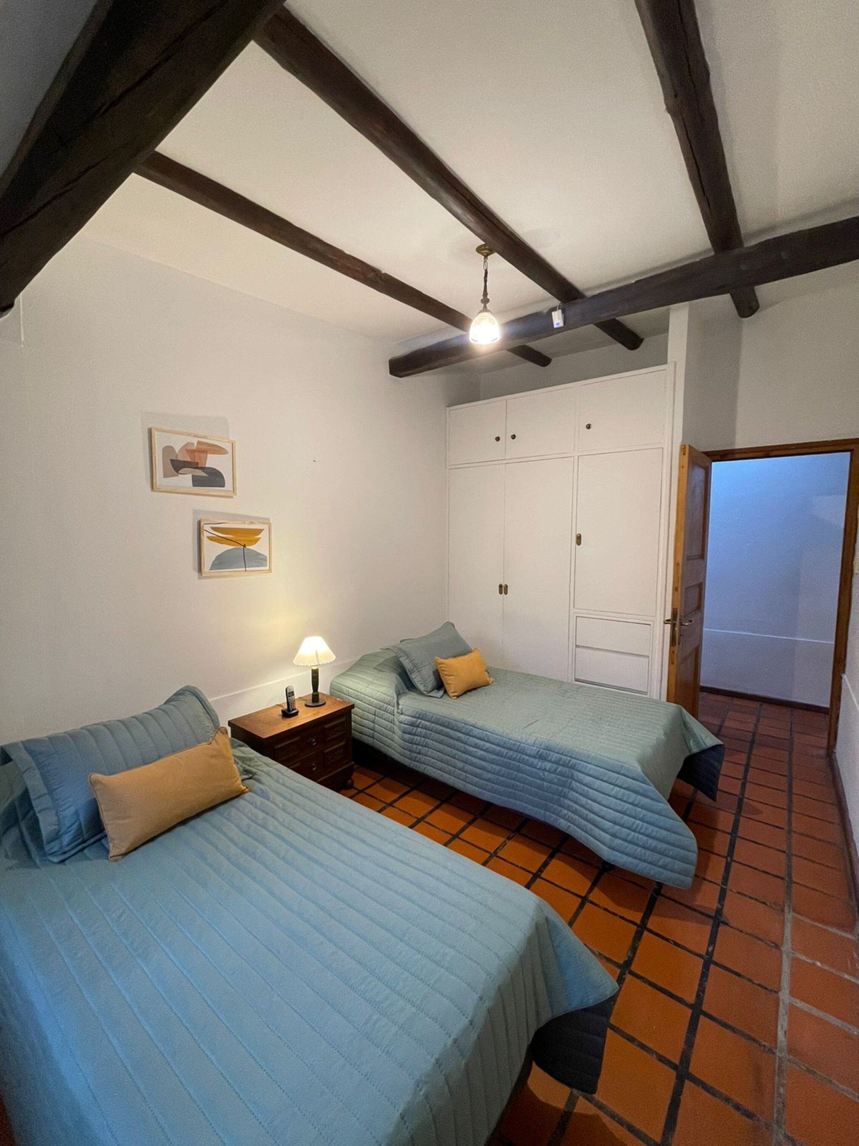 A bedroom with two beds, a wardrobe, and a ceiling fan.