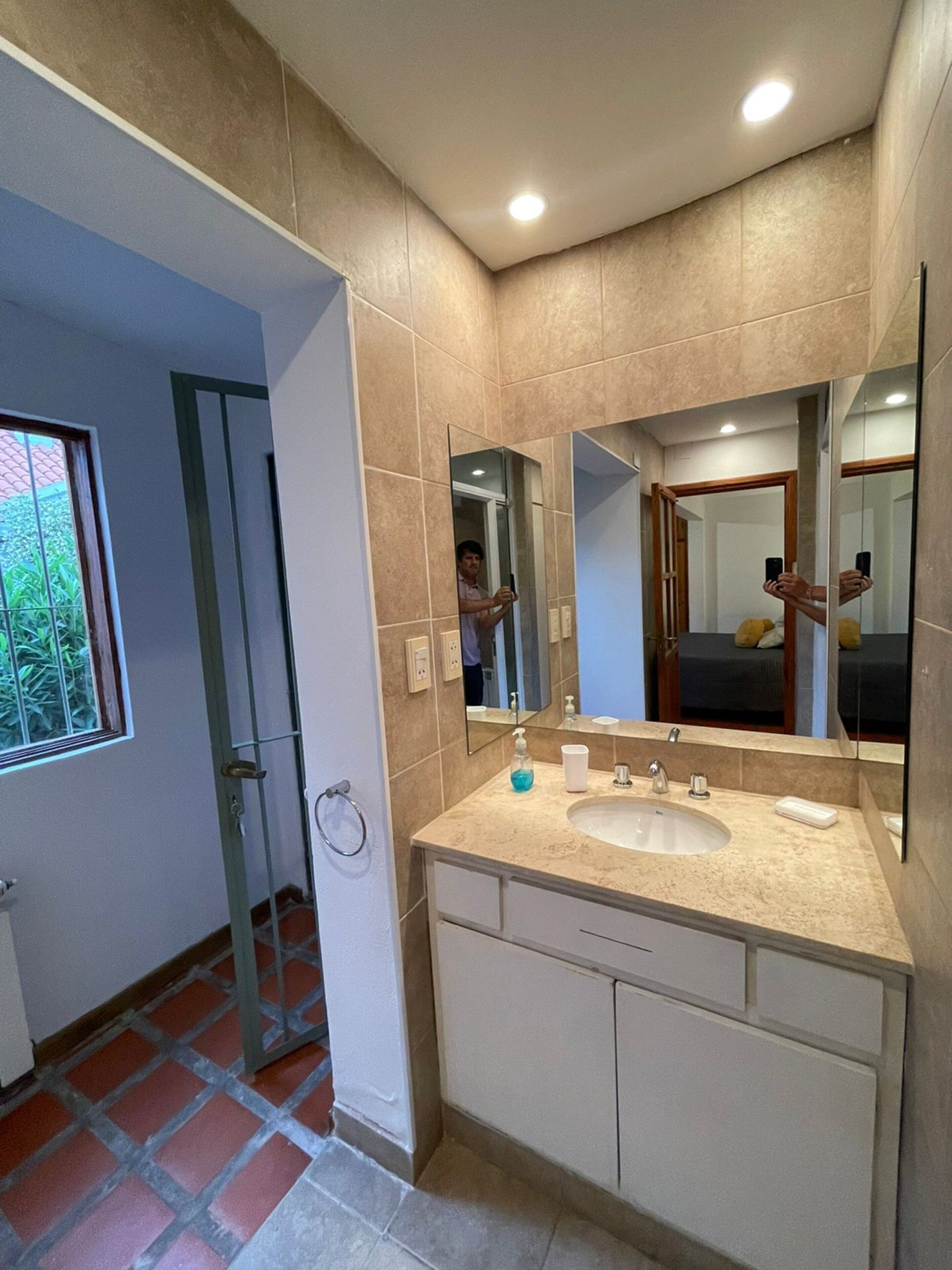 Um banheiro moderno com duas pias, um espelho grande e uma porta de vidro para o chuveiro.