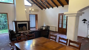 A spacious room with a large wooden dining table, several chairs, a fireplace, and a chandelier. - Casa Loria by Vilvey Turismo (Chacras de Coria)