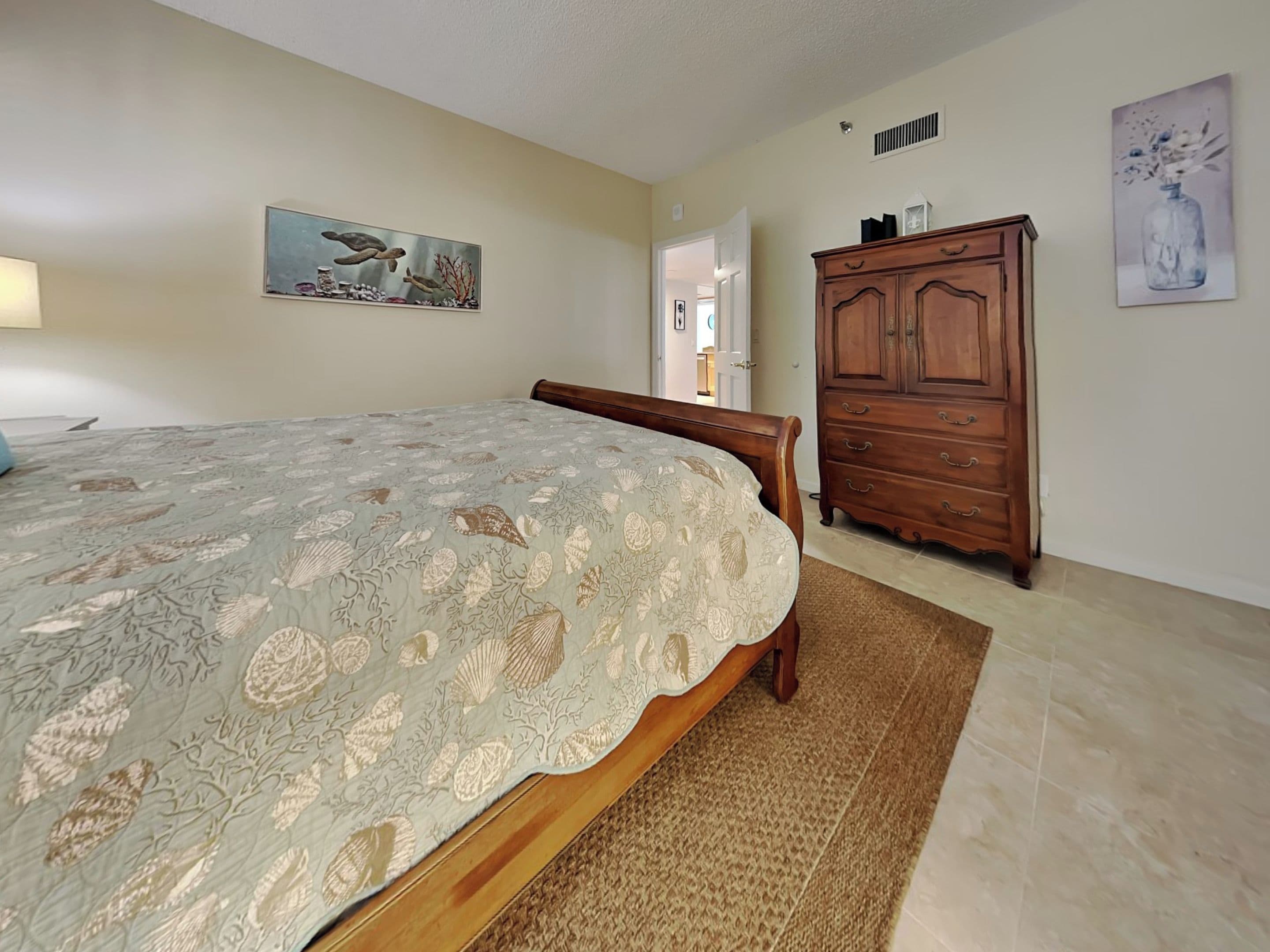 Un dormitorio con cama, cómoda de madera y un cuadro en la pared.