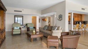 A spacious living room with a sofa, armchairs, and a coffee table. There is a kitchen area visible in the background. - Reflections on the Gulf by Distinctive Beach Rentals (Indian Rocks Beach)