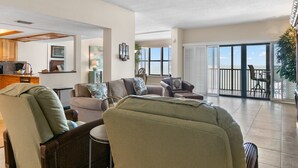 A spacious living area with a kitchen, dining area, and a balcony with a view. - Reflections on the Gulf by Distinctive Beach Rentals (Indian Rocks Beach)