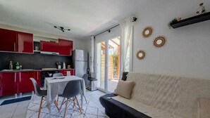 Een kleine leefruimte met een kitchenette, een eethoek en een bank.