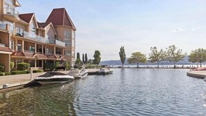 Ein Hotel am Wasserufer mit mehreren Balkonen, einer Marina mit Booten und Blick auf das Wasser und die entfernte Landschaft.