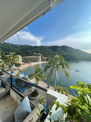 Un balcon offrant une vue sur une plage, une piscine et un paysage montagneux.