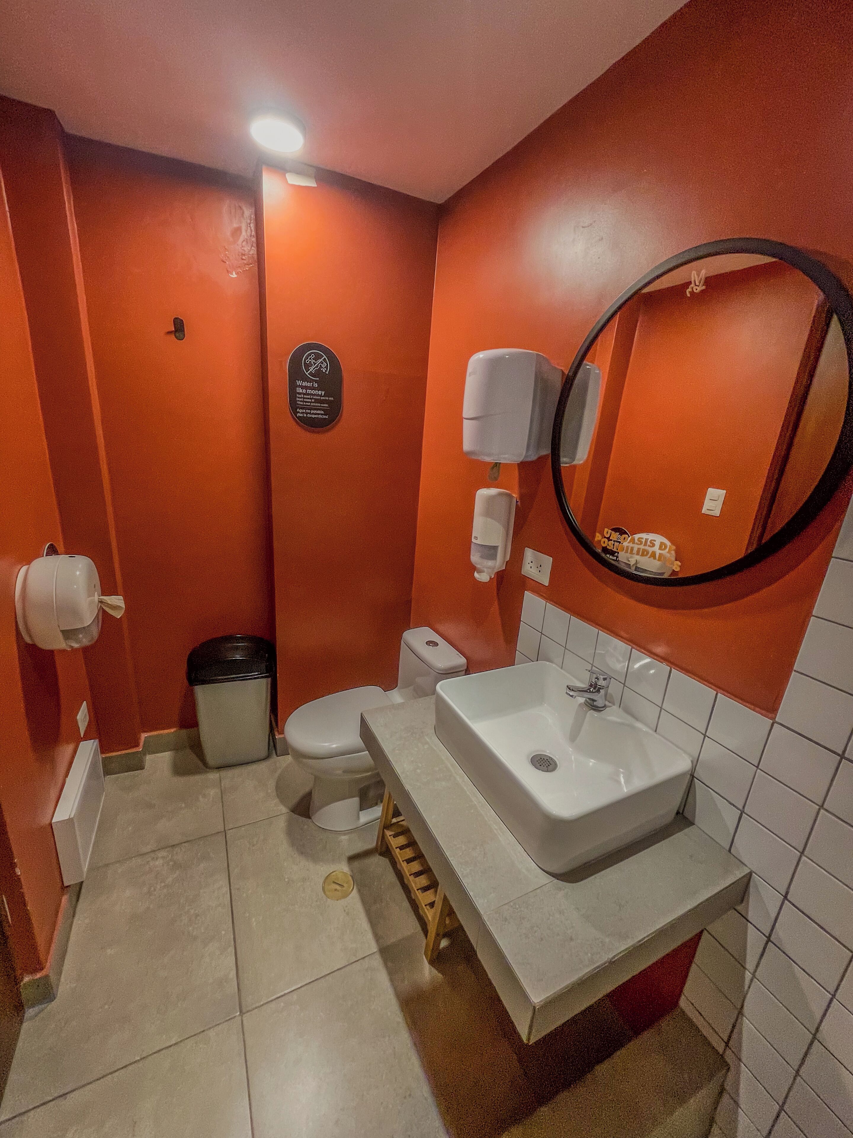A compact bathroom with a white sink, a toilet, and a trash bin.