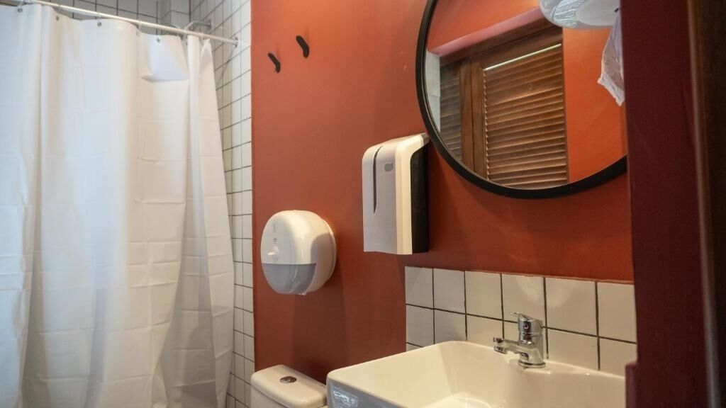 A bathroom with a white bathtub, a toilet, and a hand dryer.