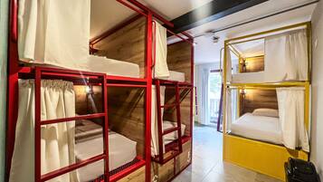 A dormitory-style room with bunk beds, wooden walls, and a tiled floor.