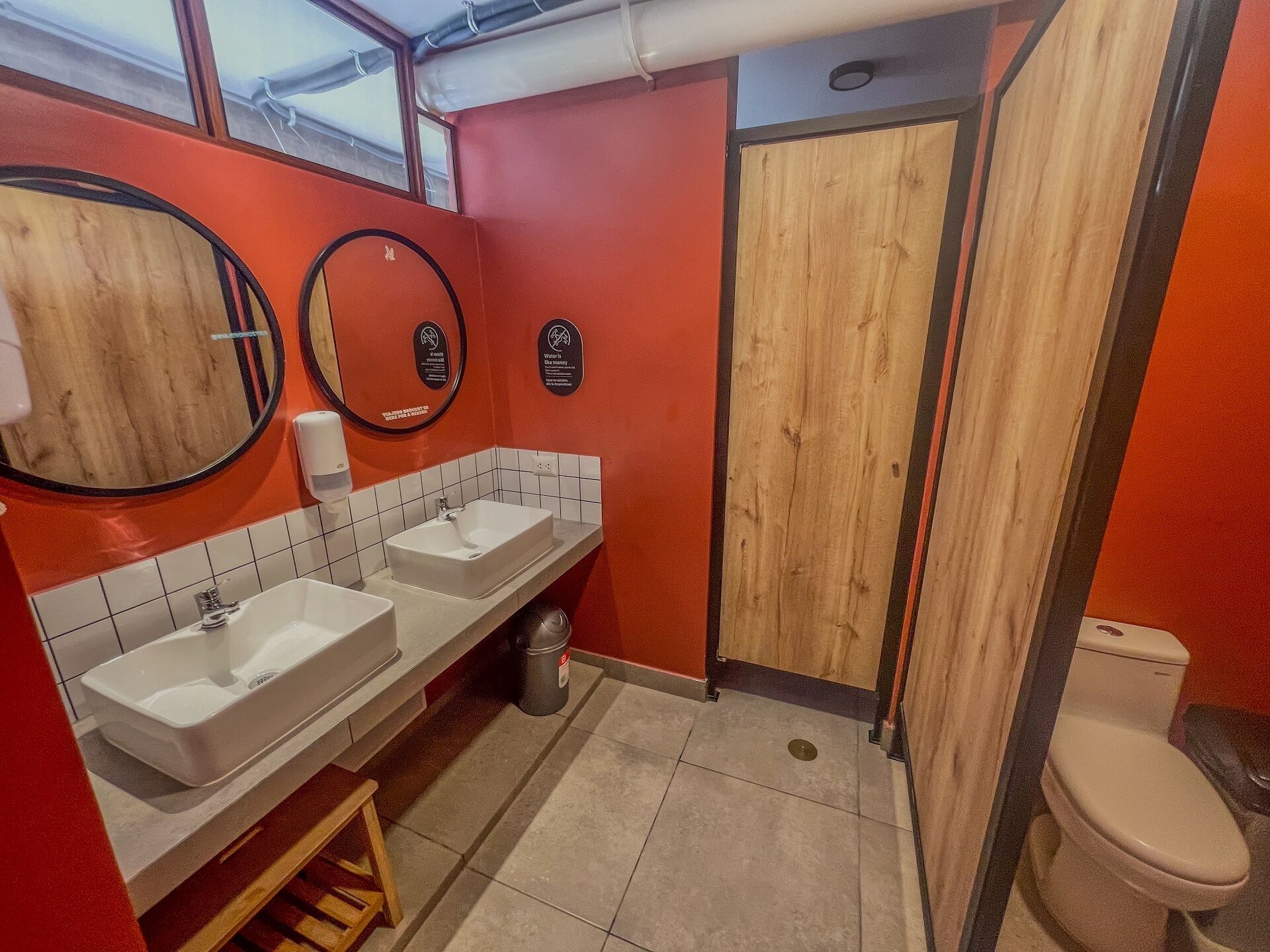 A bathroom with two sinks, a mirror, a toilet, and a wooden door.