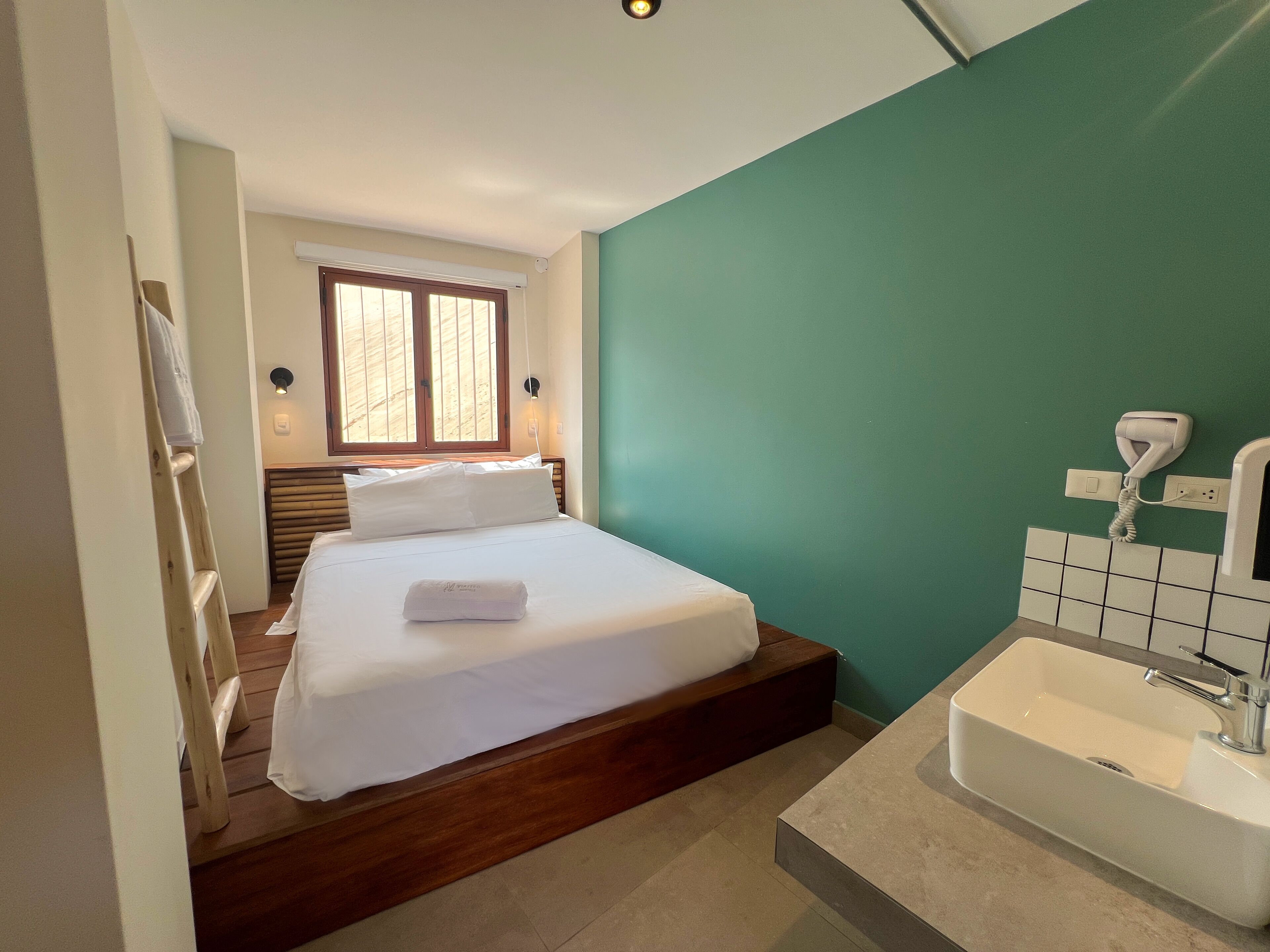 Ein Hotelzimmer mit Bett, Badezimmer mit Waschbecken und Fenster.