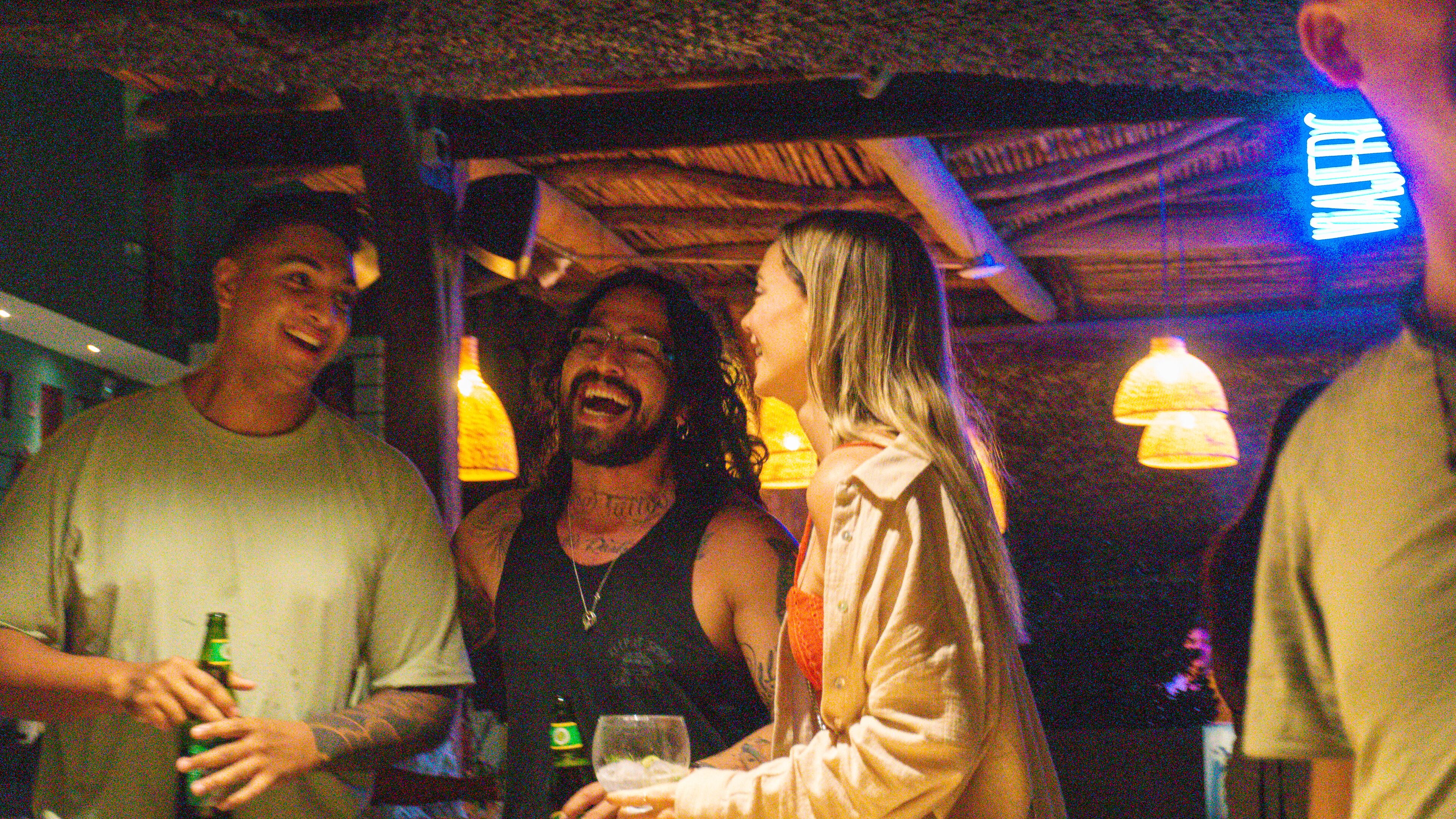 A group of people in a dimly lit indoor setting with visible hanging lights.