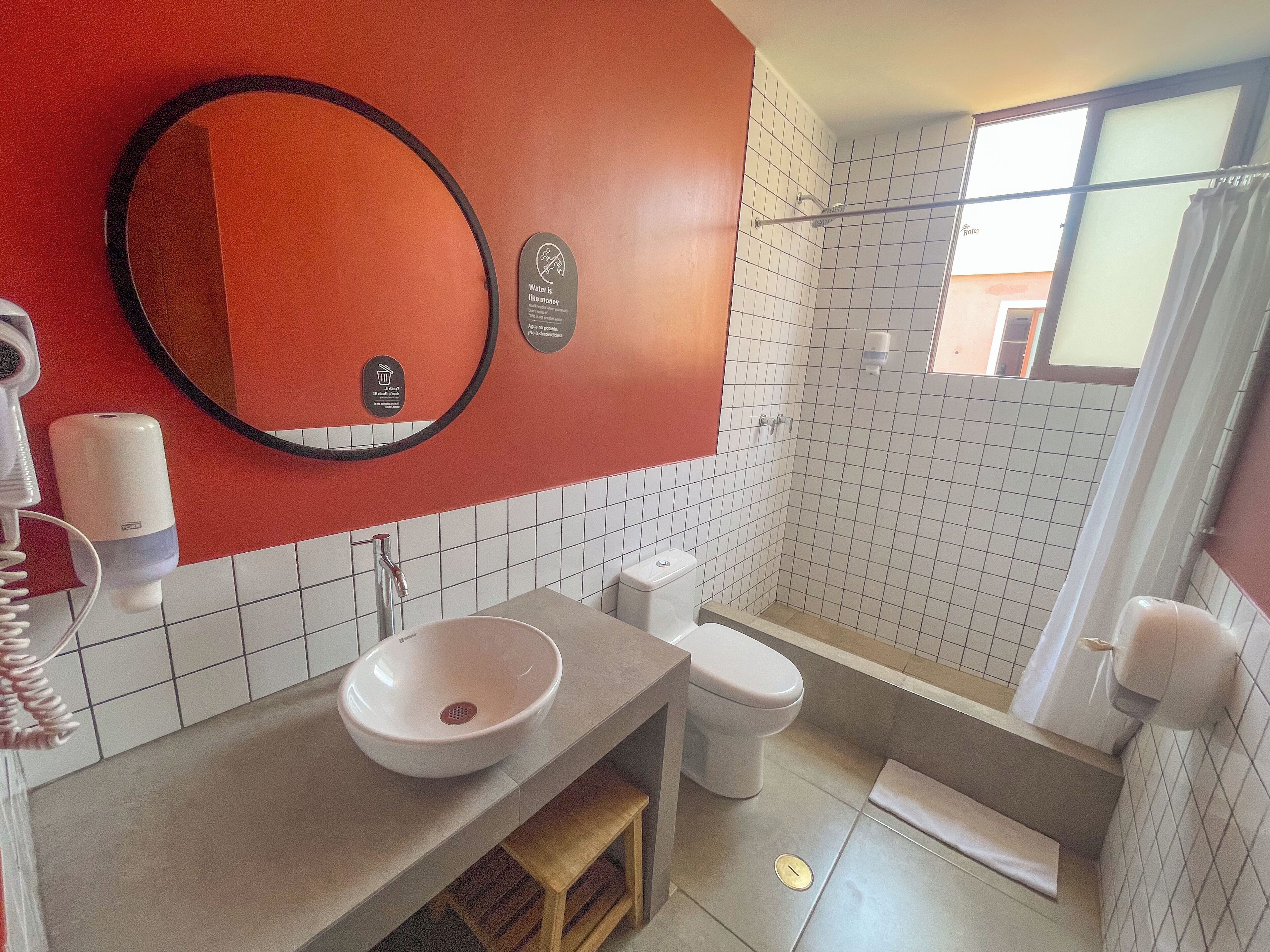 Casa de banho com lavatório, sanita e chuveiro. Há um espelho na parede e um porta-toalhas.
