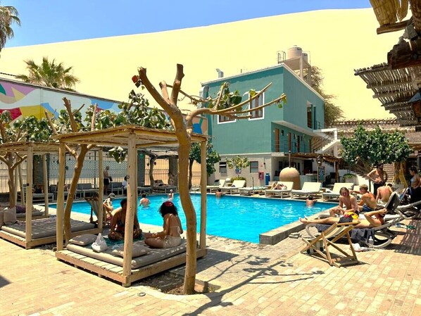 A pool area with lounge chairs and a wooden structure. - Viajero Huacachina Hostel (Ica)