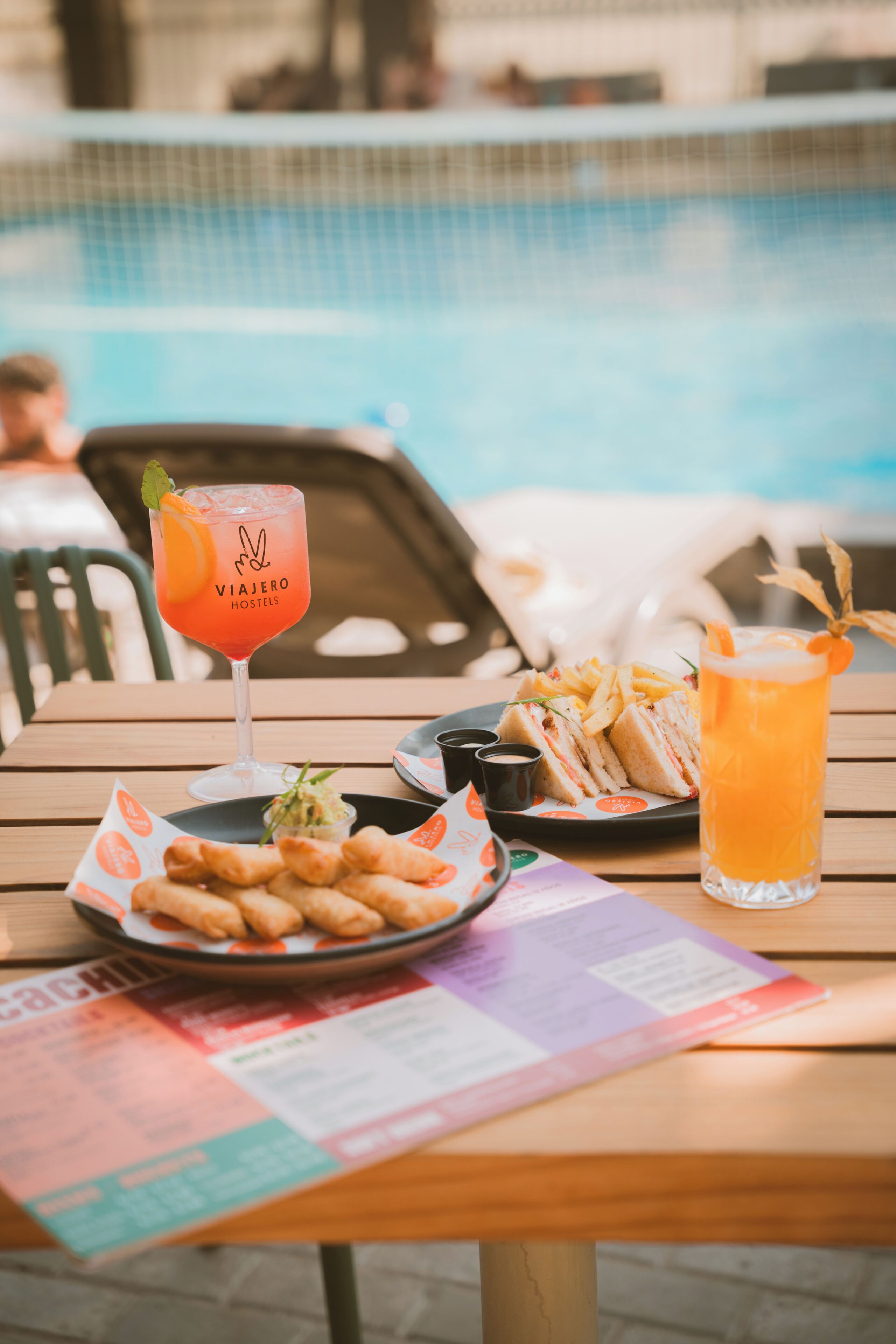 A table with a drink, sandwich, fries, and a menu.