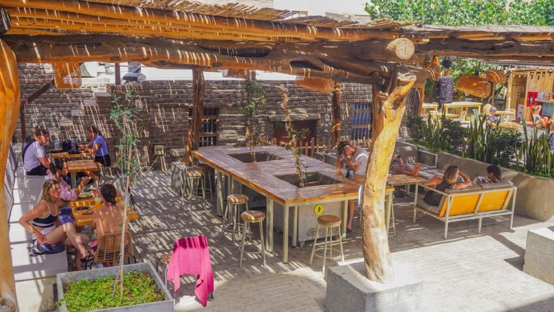 An outdoor patio area with stone walls, wooden tables, and chairs.