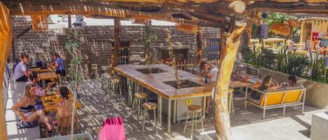 An outdoor patio area with stone walls, wooden tables, and chairs.