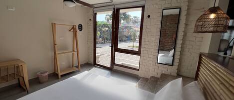 A bedroom with a bed, a ceiling fan, a wooden dresser, a mirror, and a view of the outside.
