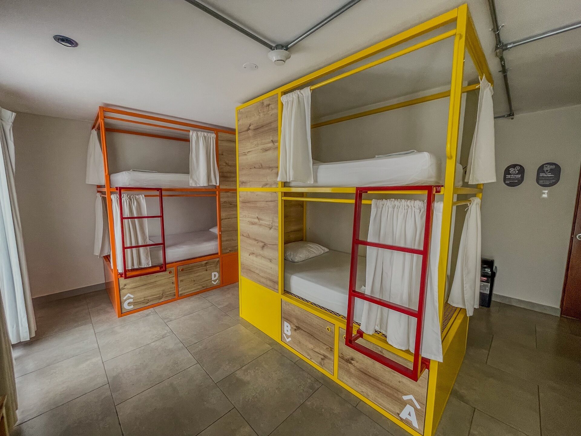 Two bunk beds with wooden frames and yellow accents, white bedding, and a tiled floor.