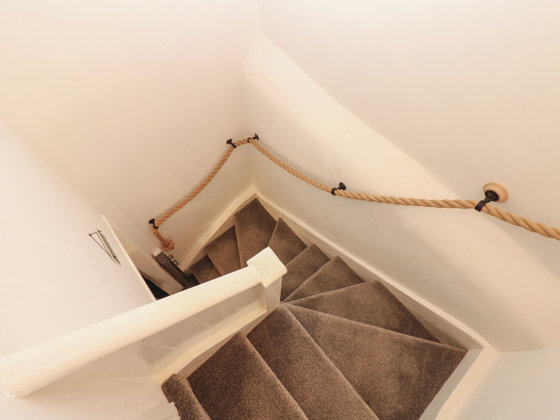 Una escalera con barandilla blanca y una barrera de cuerda.