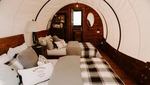 A cozy, arched room with a bed, a nightstand, a lamp, and a mirror.