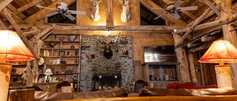 Un intérieur rustique avec des poutres en bois, une cheminée en pierre et un canapé en cuir.