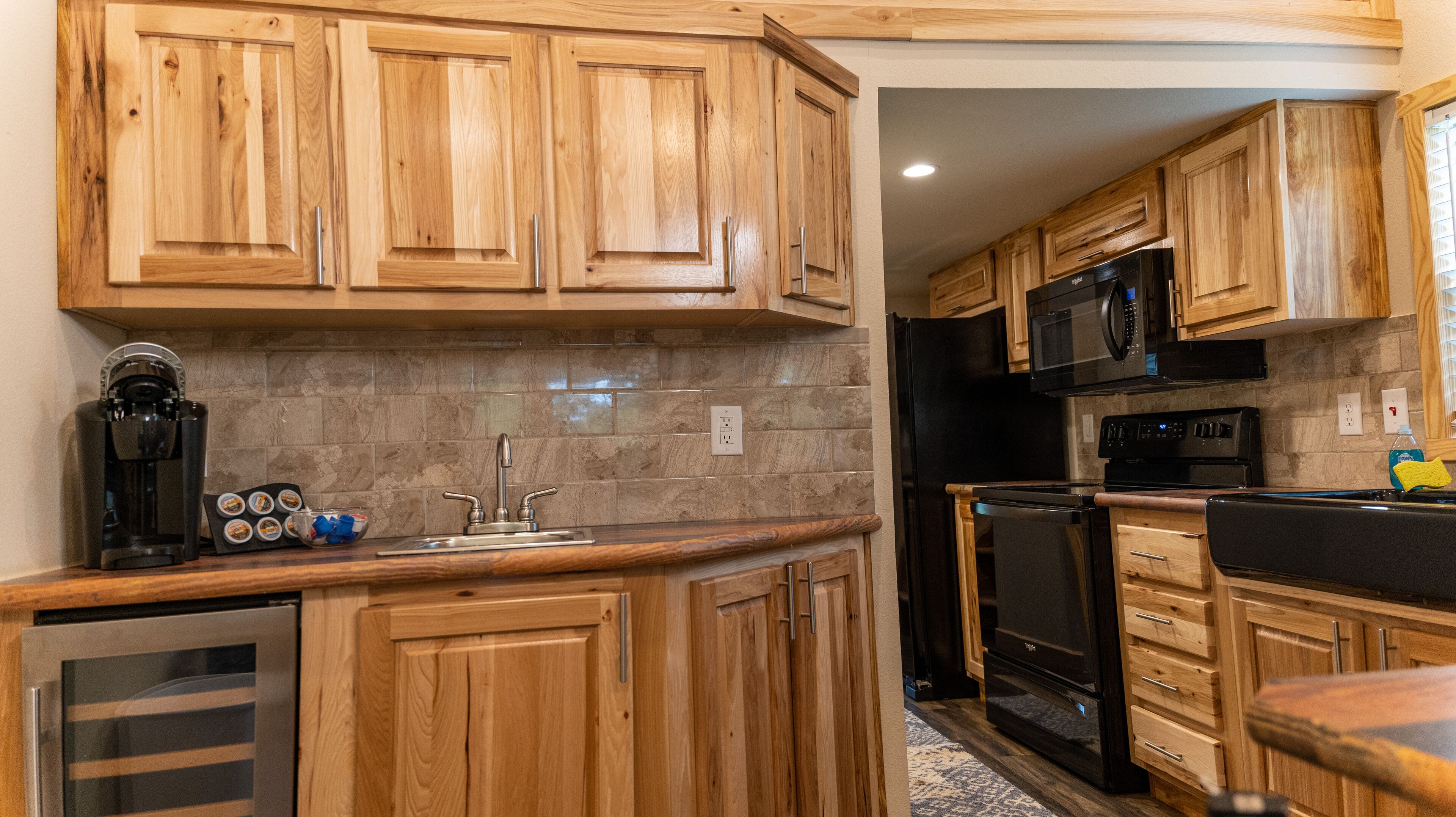 A kitchen with wooden cabinets, a stainless steel sink, a coffee maker, a microwave, and a refrigerator.