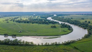 Ein Fluss schlängelt sich durch eine grüne Landschaft, auf dem Wasser ein kleines Boot.