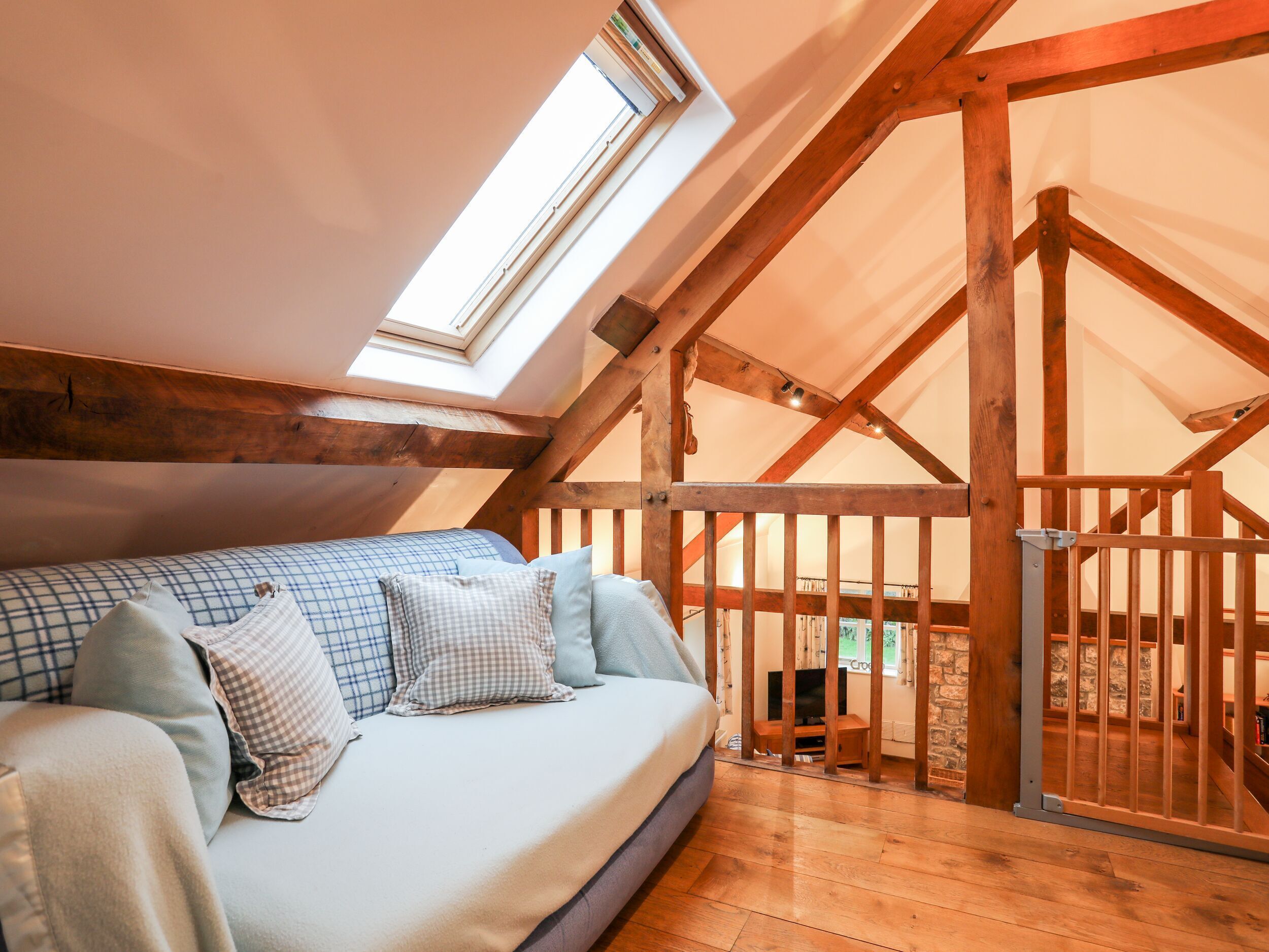 A cozy loft bedroom with a wooden ceiling and a large skylight.