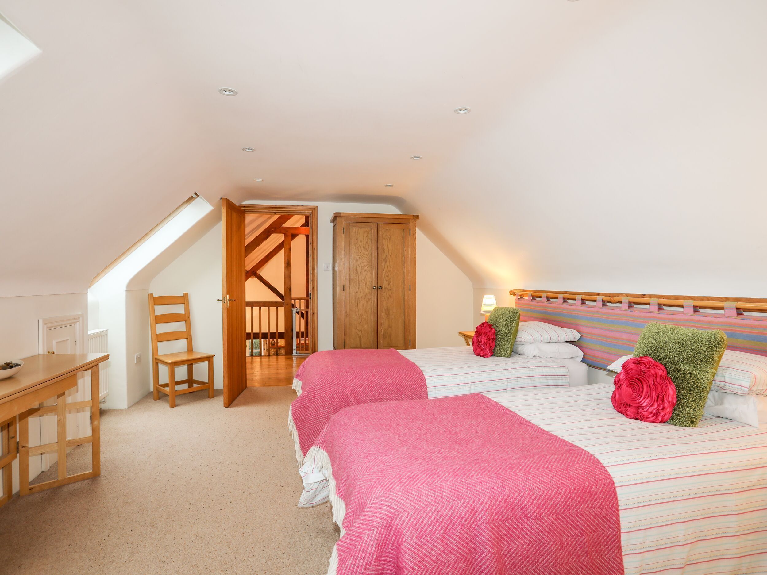 A bedroom with two beds, a desk, and a chair.