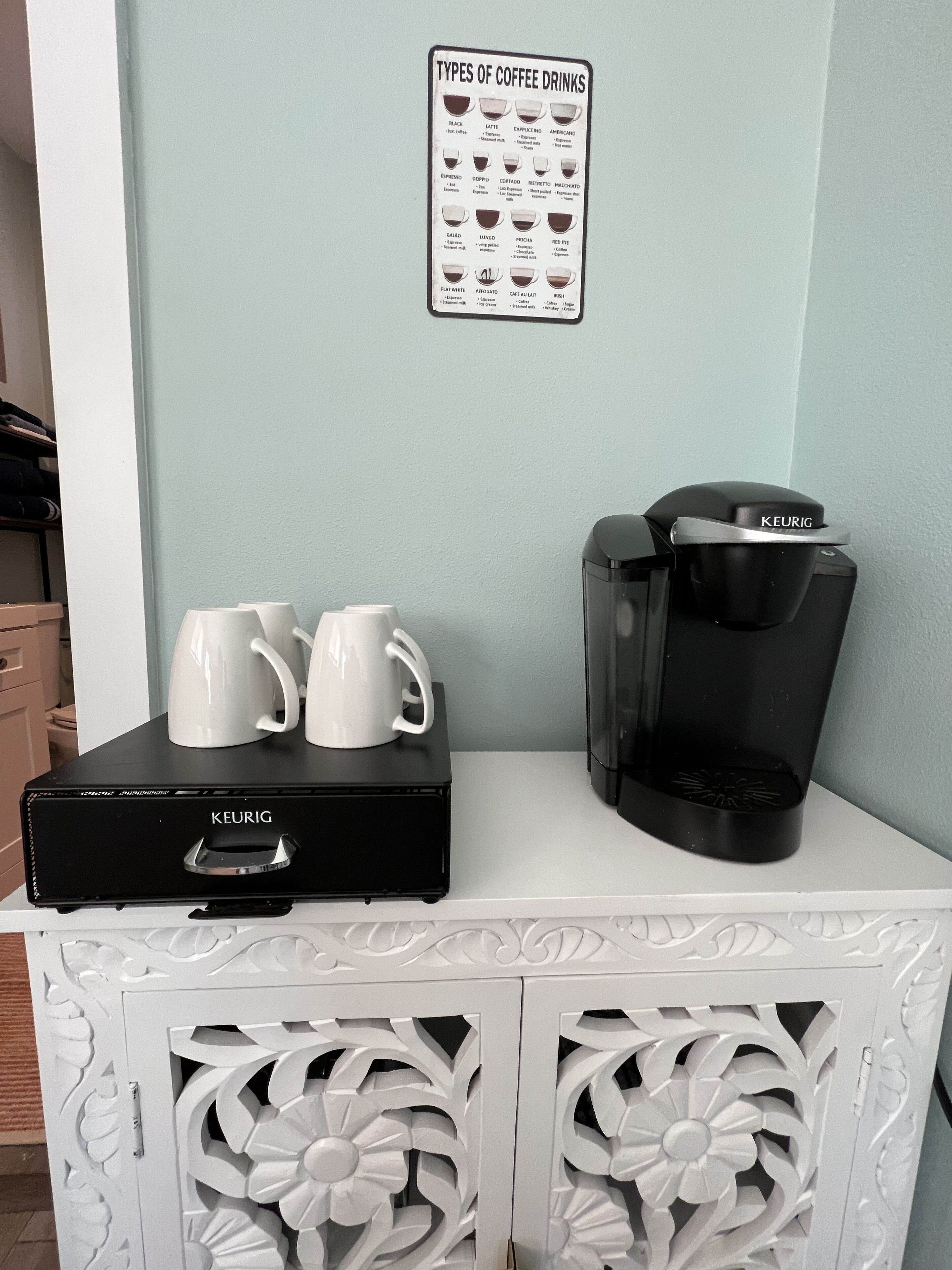 Une machine à café posée sur un meuble blanc, avec une tasse à café sur le dessus.