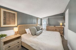 A bedroom with a bed, bedside tables, a dresser, and a large framed picture on the wall.