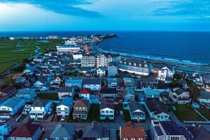 An aerial view of a coastal residential area with houses, a road, and the ocean.