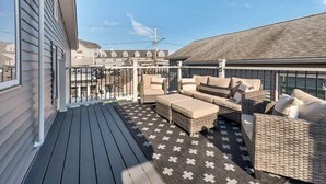 A deck with wicker furniture and a patterned rug. - The Salty Oyster - Amazing Deck and Short Walk to beach! (Hampton)