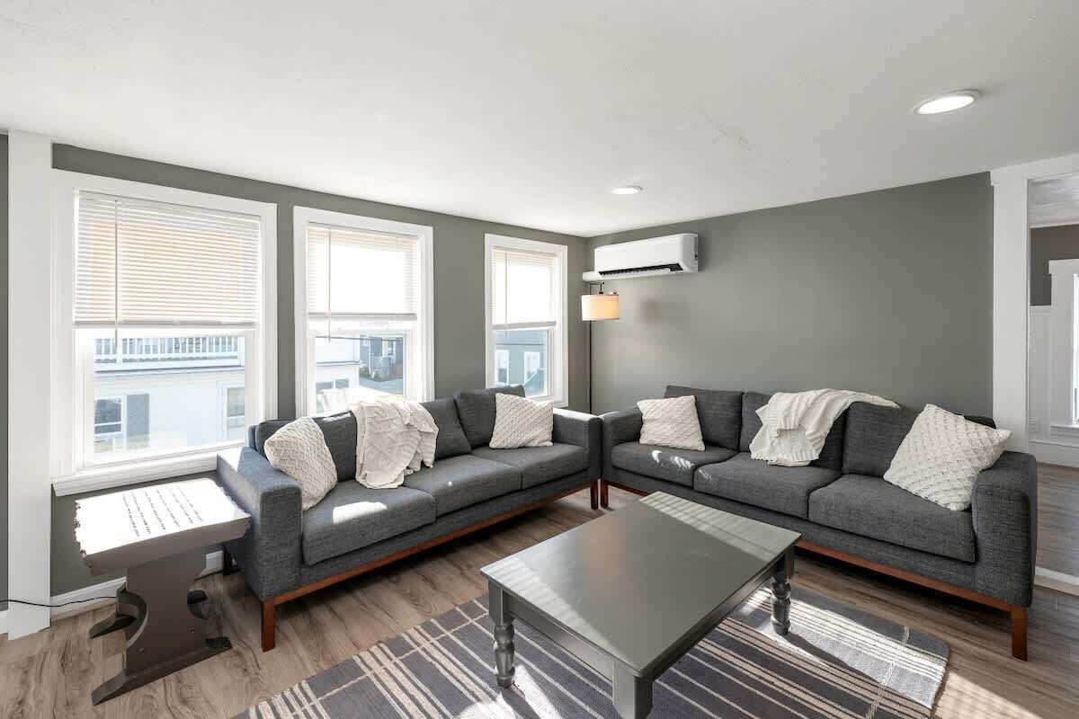A modern living room with two grey sofas, a coffee table, and a small side table.