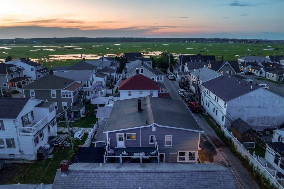 Un quartier résidentiel avec des maisons, un bâtiment central doté d’un toit rouge et, au fond, un grand espace ouvert.