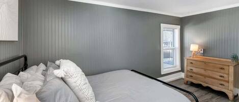 A bedroom with a bed, a dresser, and a window.