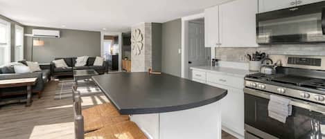 A modern kitchen with a central island, stainless steel appliances, and a seating area with a sofa and chairs.