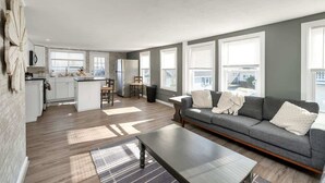 A modern apartment with a kitchen, dining area, and living room. - The Salty Oyster - Amazing Deck and Short Walk to beach! (Hampton)