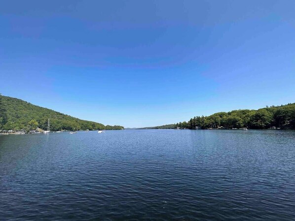 A calm lake with boats, surrounded by forested hills. - Alpine Suite - Walk to Lake Sunapee and Restaurants (Sunapee)