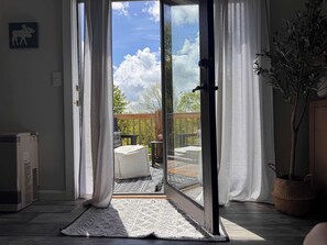 A room with a sliding glass door leading to an outdoor deck. - Alpine Suite - Walk to Lake Sunapee and Restaurants (Sunapee)