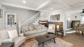 A living room with a sofa, armchair, coffee table, and a staircase leading to another level. - The Fleet -  Perfect Location Near Beach & Boardwalk (Hampton)