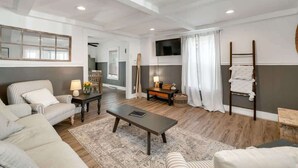 A modern living room with a sofa, armchair, coffee table, TV, and a ladder against the wall. - The Fleet -  Perfect Location Near Beach & Boardwalk (Hampton)