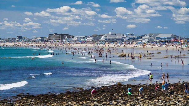 A beach with people, buildings, and a rocky shoreline. - Riptide Retreat - Walk to Hampton & Seabrook Beach! (Seabrook)