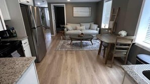 Eine moderne Küche mit Einbaukühlschrank, ein Essbereich mit Tisch und Stühlen sowie ein Wohnzimmer mit einer Couch.