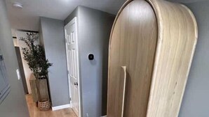 Ein Flur mit einem Holzschrank, einer grauen Tür und einer Pflanze.