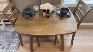 Ein Holztisch mit schwarzen Tellern, klaren Gläsern und einer floralen Tischdekoration.