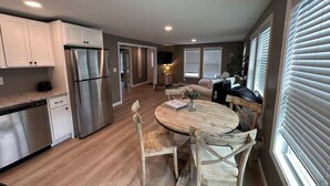 Una cocina moderna con un refrigerador de acero inoxidable, una mesa de comedor de madera y sillas.