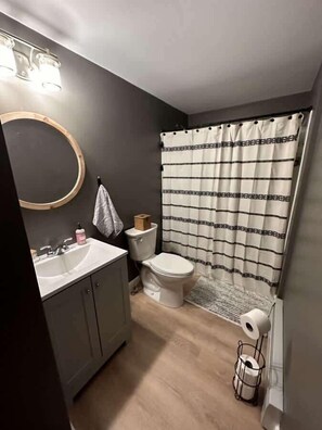 A bathroom with a sink, toilet, and shower curtain.